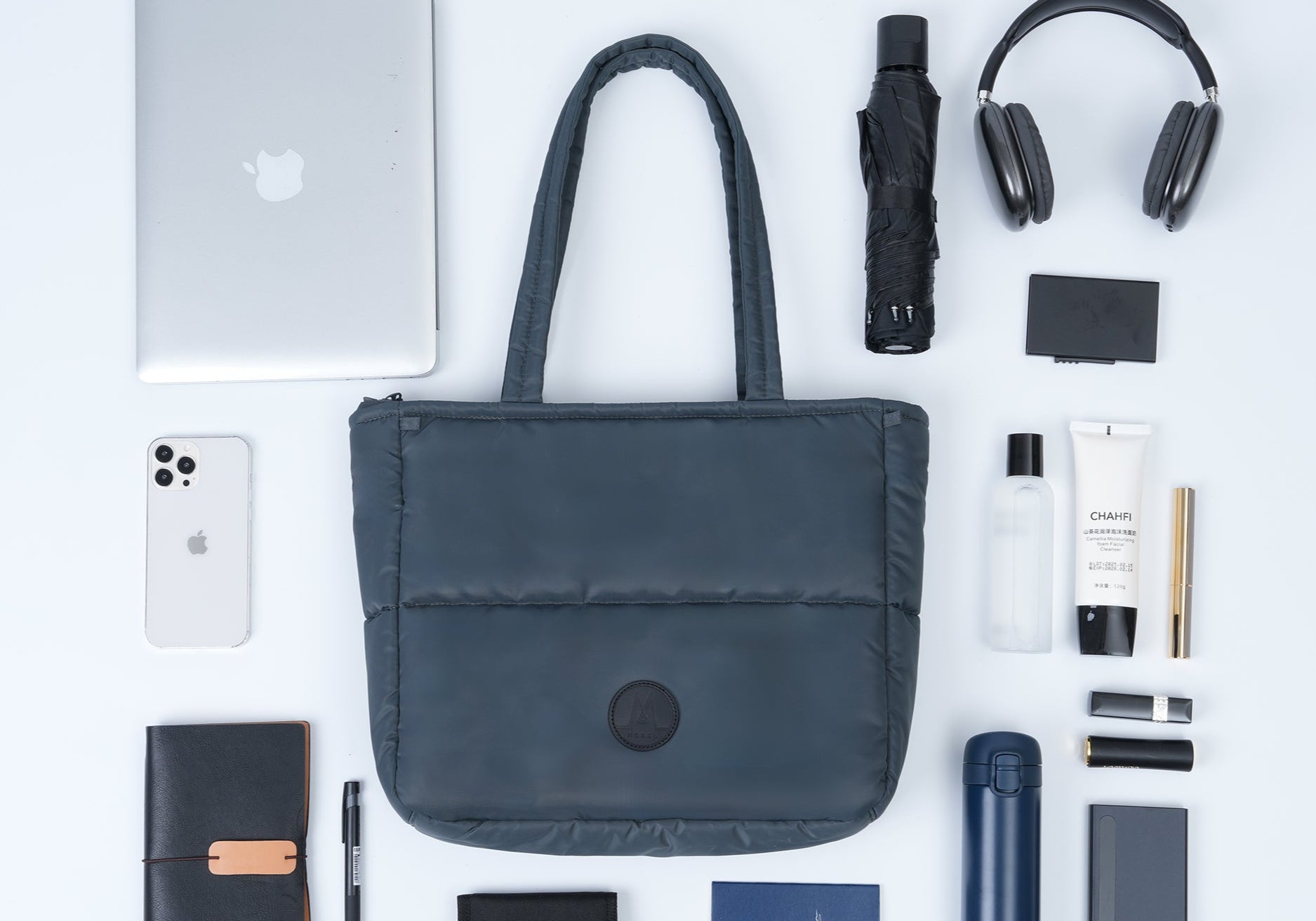 Collection of travel items including a laptop, phone, wallet, and bag on a white background