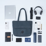 Collection of travel items including a laptop, phone, wallet, and bag on a white background